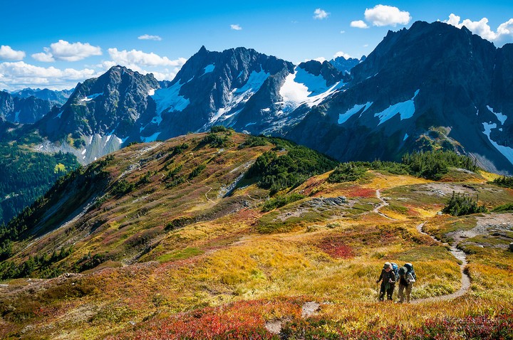 Couple with backpacks hiking on Sahale Arm Trail, Cascade Pass, North Cascades National Park, Washington.